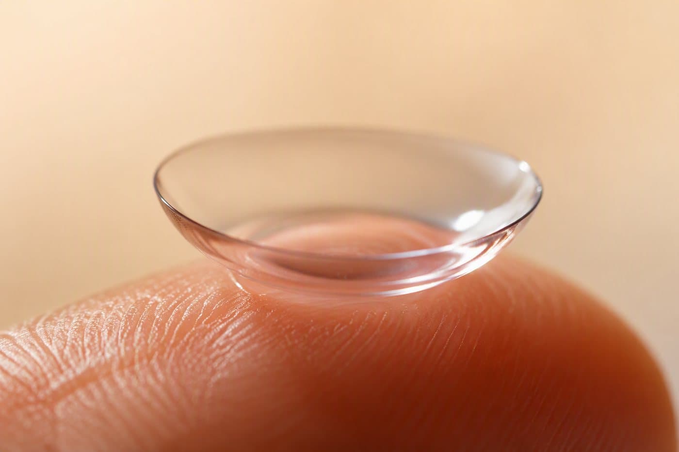 A daily contact lens catching light on a fingertip